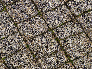 Detailed close-up of textured stone pavement with small pebbles and moss in between