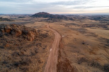 A desert landscape glows at sunset over barren terrain. Aerial view of a winding dirt road through a barren landscape.