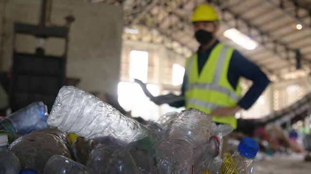 Blurred image of an environmental engineer inspecting the compression of waste plastic before it is sent for sale at a waste separation plant.