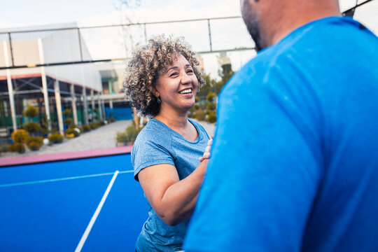 Portrait of woman playing padel with her friend on outdoor court.