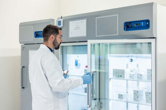 Scientist opening laboratory refrigerator containing medicines - Powered by Adobe