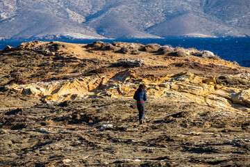 Woman standing alone on the cliffs from an island in the middle of the sea. Concept image for...