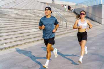 Jogging couple enjoying exercise on outdoor steps in a city park during a sunny afternoon