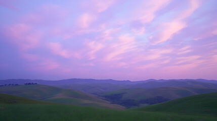 Waves of lavender-colored clouds stretching across the sky above serene rolling green hills during sunset