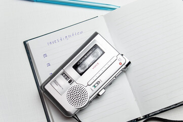 A tape recorder with buttons is on a notebook labeled investigation. the white background and...