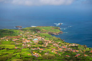 View of Atlantic ocean coastline of Flores Island, Azores, Portugal, from Miradouro de Ponta Delgada. White houses, fields, rocks and water. Nature, landscape photography at sunny day.