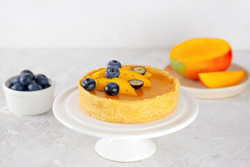 Mango tart with blueberry on a stand on a table. Sugar, sugar substitutes, lactose and gluten free. Vegan dessert.