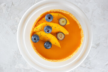 Mango tart with fresh blueberry in a plate on a table. Sugar, sugar substitutes, lactose and gluten free. Vegan dessert. Top view.