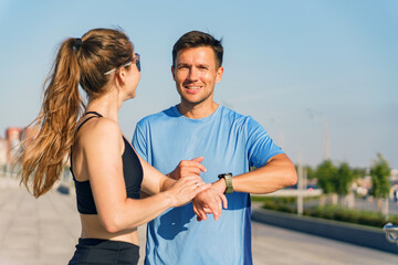 Fitness enthusiasts share tips while checking workout progress on a sunny day outdoors in the city