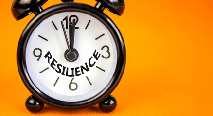 Resilience symbol. Concept word Resilience on beautiful orange paper. Beautiful orange paper background. Black alarm clock. Business resilience concept. Copy space.