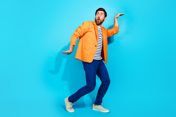 Charismatic young man in vibrant orange jacket striking a playful pose against a vibrant teal background