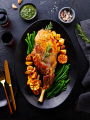 Roasted lamb leg with potato and green bean. Black background. Top view.