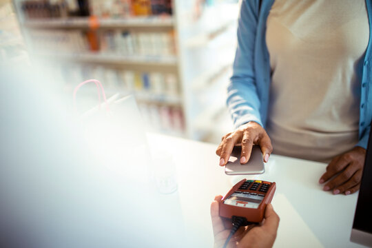 Woman making contactless payment at pharmacy counter