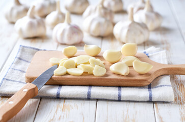 Fresh garlic cloves and bulbs on a cutting board.