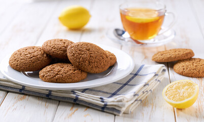 Tasty oatmeal cookies and tea on a light kitchen table, selective focus.