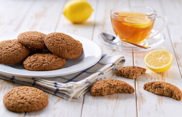 Low-calories oatmeal cookies and tea on a light kitchen table, selective focus.
