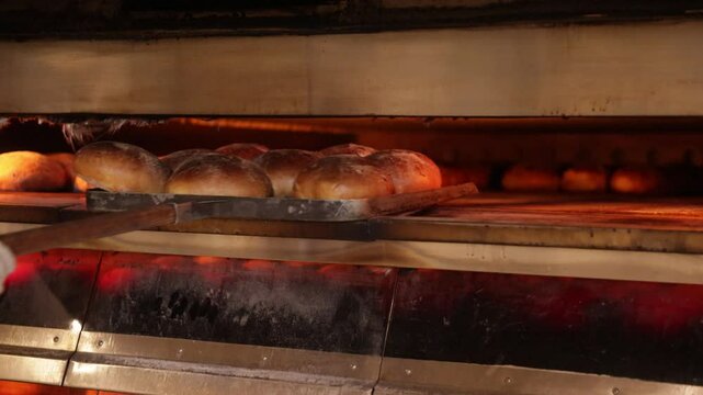 Baker taking freshly baked bread