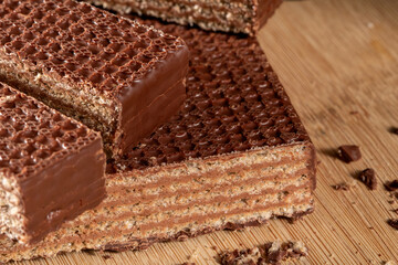 Wafer chocolate cake cut into pieces on kitchen table extreme close up top view