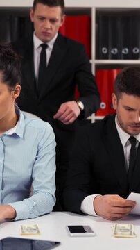 Handsome Boss businessman collect some money from his employee visual. Like per cent from salary. He put it in pocket and go away. Sad collegues injustice. 4k ultra hd. Vertical Shot.