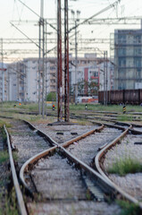 Railroad track switch in an urban environment. Tracks converging and diverging, with buildings and power lines in the background.
