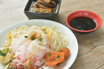 steamed large rice noodles topping slice fried Chinese sausage and crispy pork belly with bean sprout dressing black soy sauce on plate dipping sour soybean sauce