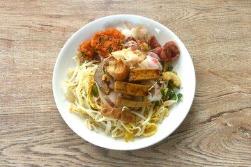steamed large rice noodles topping slice fried Chinese sausage and crispy pork belly with bean sprout dressing black soy sauce on plate dipping sour soybean sauce