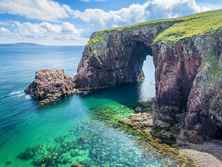 Coastal sea arch with turquoise water and green cliffs under a bright sky