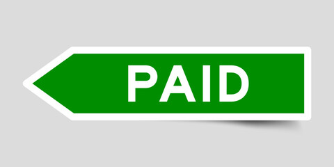 Green color arrow shape sticker label with word paid on gray background