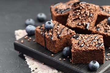 Delicious chocolate puffed rice bars and blueberries on gray textured table, closeup