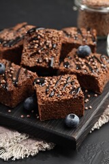 Delicious chocolate puffed rice bars and blueberries on gray textured table, closeup