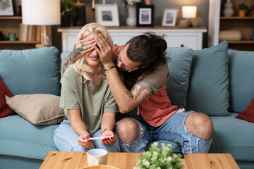 We become parents. Couple feeling happy after taking a home pregnancy test. Happy young couple man...