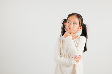 Portrait Asian kid girl deep in thought, standing with chin in hand, pondering a question. Studio...
