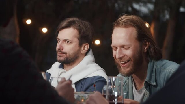 Friends enjoying evening meal outdoors under string lights