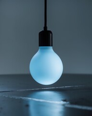Soft glowing blue light bulb with reflection on dark surface
