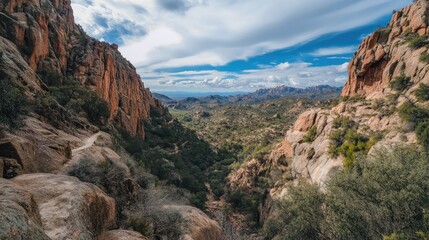 Naklejka premium Scenic outdoor view of rustic landscape featuring rocky terrain under a dramatic sky with distant mountains and lush vegetation