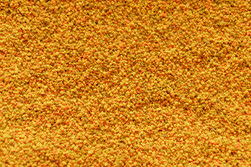 Close up texture of raw yellow bee pollen grains creating a natural organic pattern. Can be used as a background for healthy food and supplement themes.