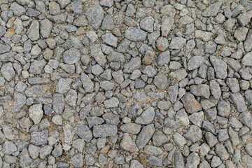 A detailed close-up texture of small gray gravel stones, evenly spread across the frame, creating a rugged and earthy surface, ideal for backgrounds or construction themes.
