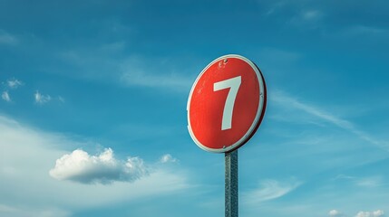 Red Circular Street Number Sign Featuring the Number Seven Against a Clear Blue Sky with Soft Clouds