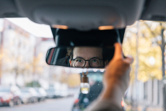 Businesswoman adjusting rearview mirror while driving to work