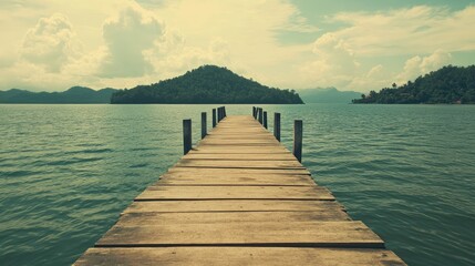 Scenic vintage wooden pier extending into serene waters with distant island backdrop ideal for...