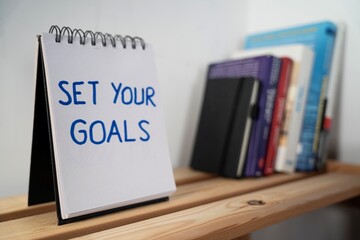 otwarty notes na półce z kartką na której zapisany jest tekst: Set your goals © siwyk