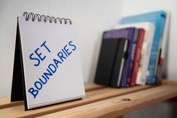 otwarty notes na półce z kartką na której zapisany jest tekst: Set Boundaries  © siwyk