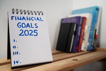 otwarty notes na półce z kartką na której zapisany jest tekst: Financial Goals 2025  © siwyk
