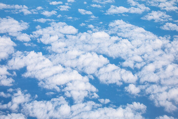 View of a sky filled with numerous fluffy white clouds against a bright blue background. Beauty and...