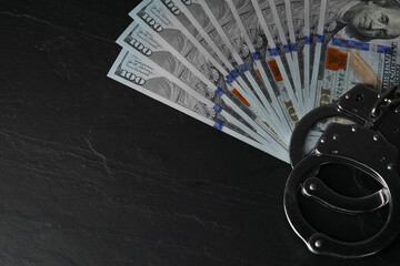 Corruption. Dollar banknotes and handcuffs on black table, top view. Space for text