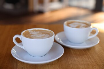 Cups of aromatic coffee on wooden table in cafe, closeup