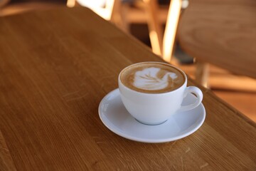 Cup of aromatic coffee on wooden table in cafe, closeup. Space for text