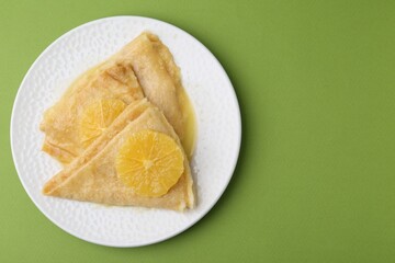 Delicious Crepes Suzette on green background, top view. Space for text