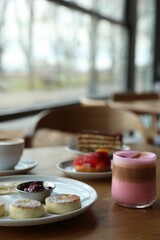 Delicious cottage cheese pancakes, desserts and aromatic coffee served on wooden table in cafe, closeup