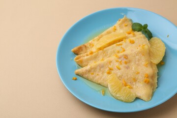 Plate with tasty crepes Suzette on beige table, closeup. Space for text